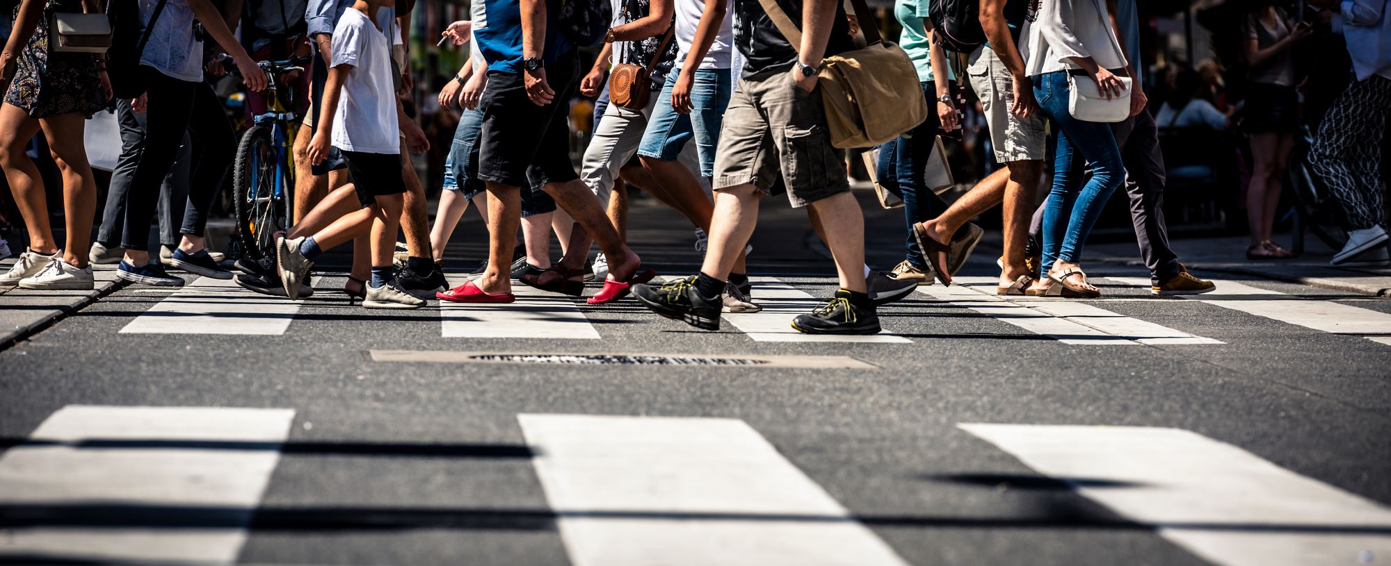 People crossing a city street in daylight, seen at street level