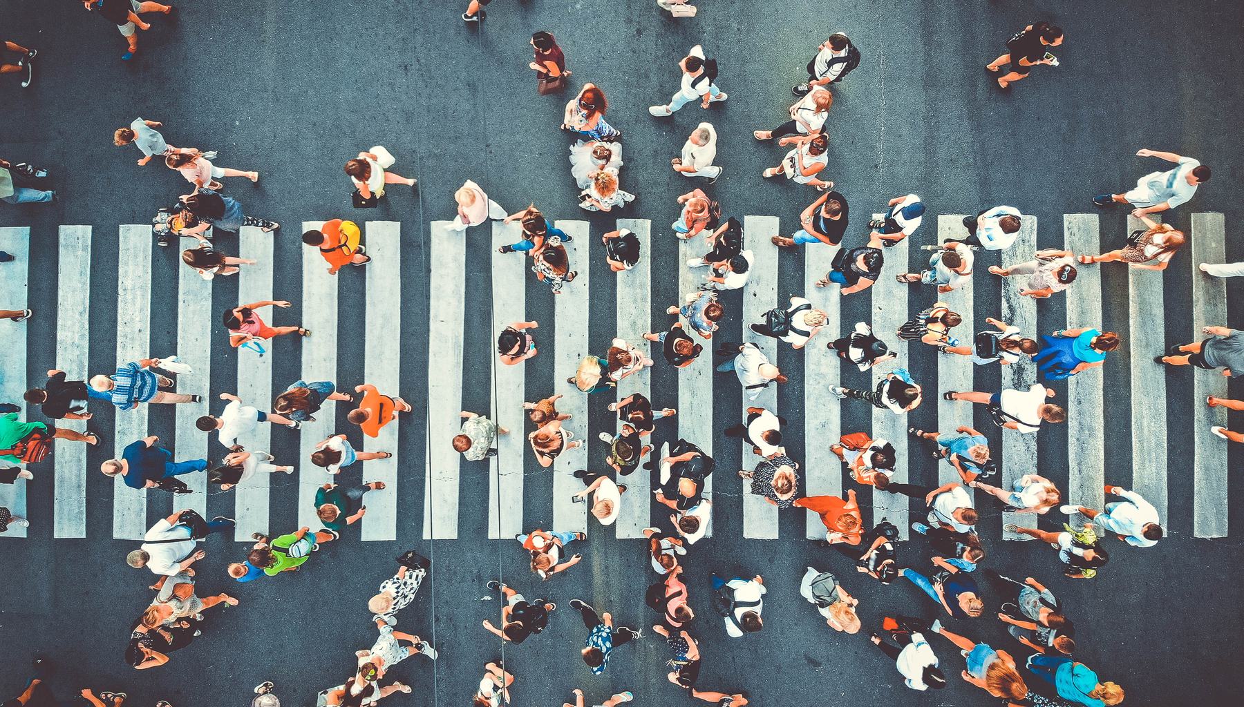A crowd of people crossing a city street, seen from directly above